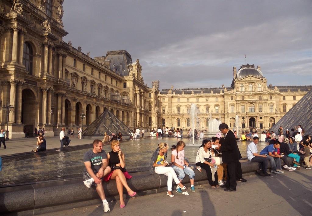 People sit inside the Louvre on a nice July day.