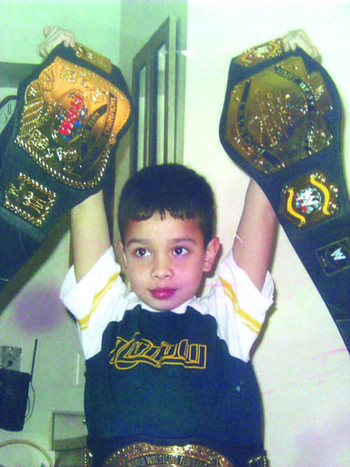 A young Daniel Critchfield poses with two faux championship belts.