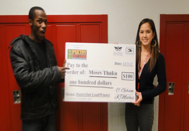 English teacher Kathleen Mathis presents senior Moses Thuku with his $100 award.