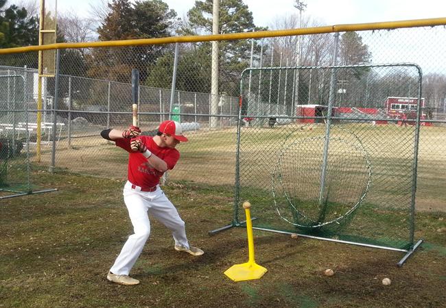 Varsity baseball player, senior Nolan Gilbert practices his hitting off a tee during practice.