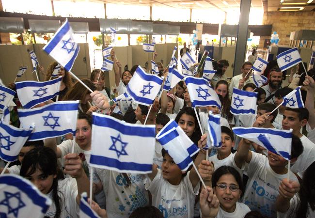 Israeli children wave flags to welcome newcomers at an airport. 