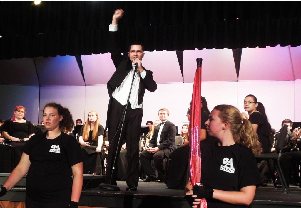 Band director Adam Hilkert addresses the audience during the symphonic band and marching atoms fall concert.