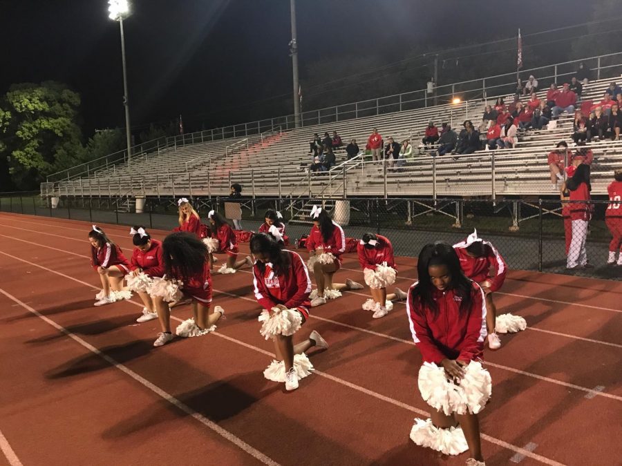 The varsity cheerleaders pose to show how some of them a knee during the national anthem. 