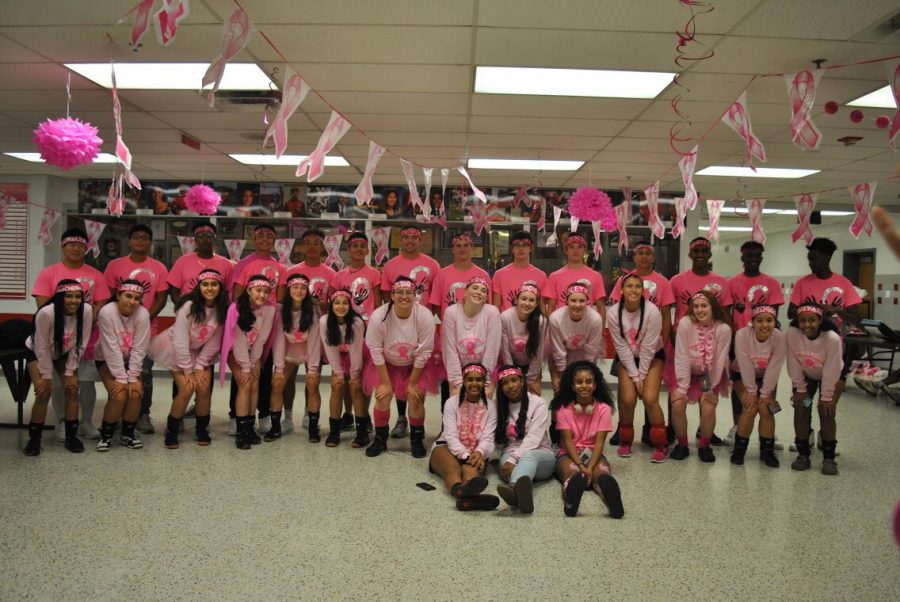 Varsity volleyball team and their partners post game, participate in Breast Cancer awareness. 
