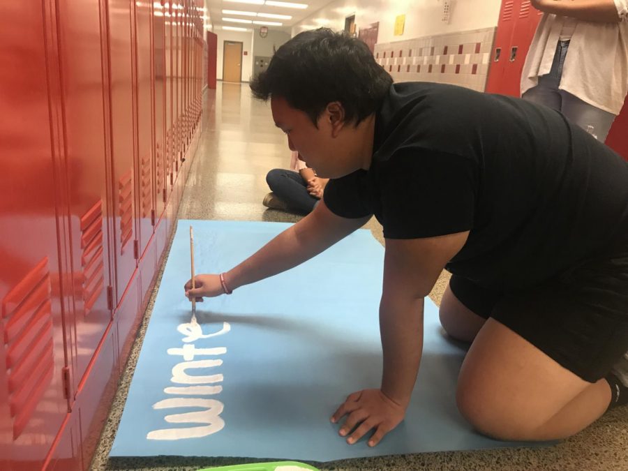 Senior Han Gyul Chang paints a  poster promoting the upcoming winter formal during pride time.
