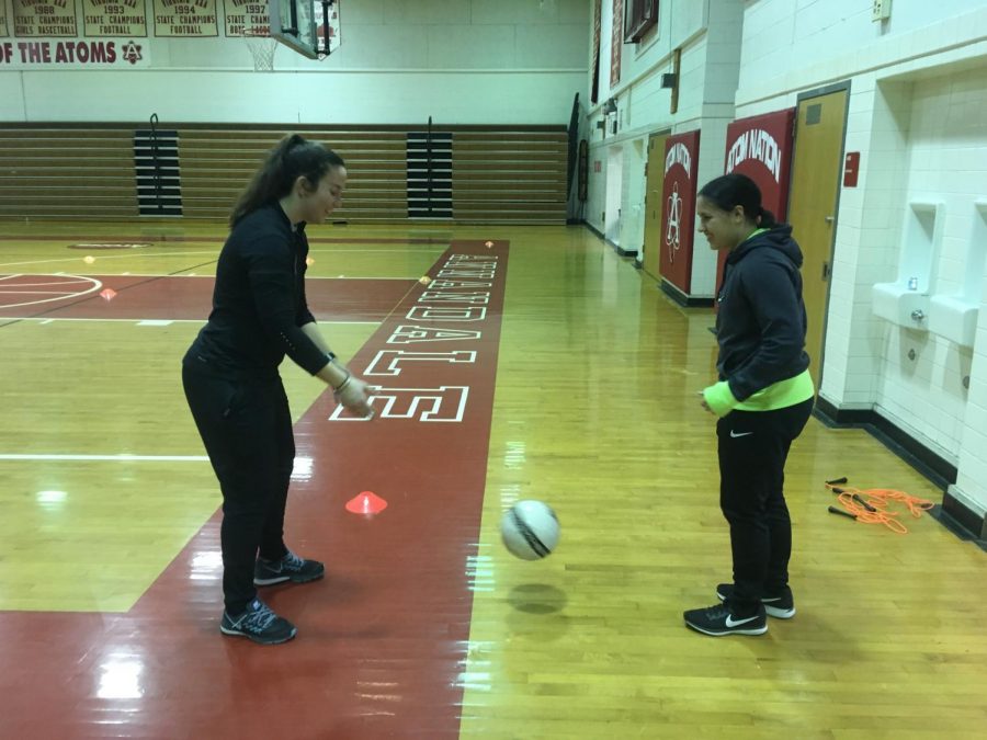 Coach Ottavio practices kicking the ball with sophomore Madison Cruz.