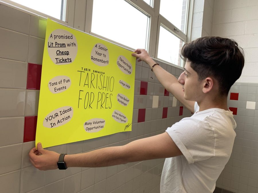Junior Tarik Darweish hangs a poster in the hallway as part of his campaign for president of the Class of 2020.