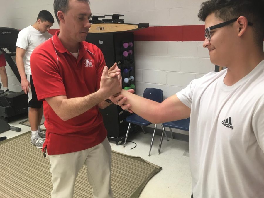Athletic trainer Ryan Hughes helps freshman Romeo Velez with a wrist injury. “I hurt my wrist playing baseball,” Velez said, “Mr. Hughes really helped me. He used a heating pad and a special technique to heal it.”