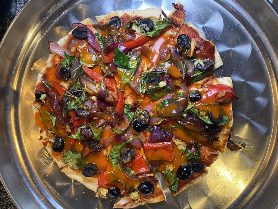 Junior Danya Khreshi makes a vegan pizza topped with olives, peppers, onions, spinach and buffalo sriracha.