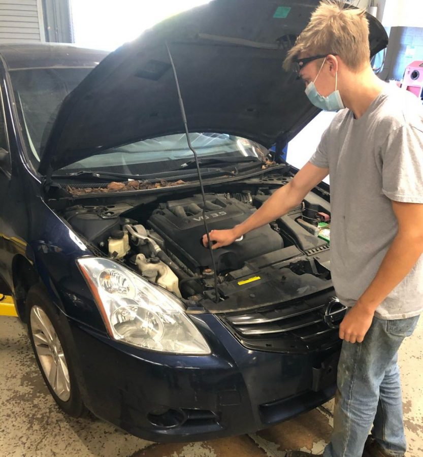 Senior Nicholas Pemberton works on a car in his Auto Tech class. “I definitely missed being in the shop,” Pemberton said. “It’s better than doing the online lessons.” He will continue attending in-person classes on Mondays even though the next group of students is no longer returning to school because of an uptick in COVID-19 cases.