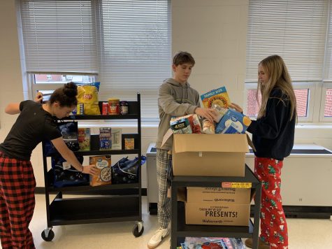Juniors Colin McGee and Jana Russell work with freshman Sophia Sewall to organize food items for the Winning4giving contest.
