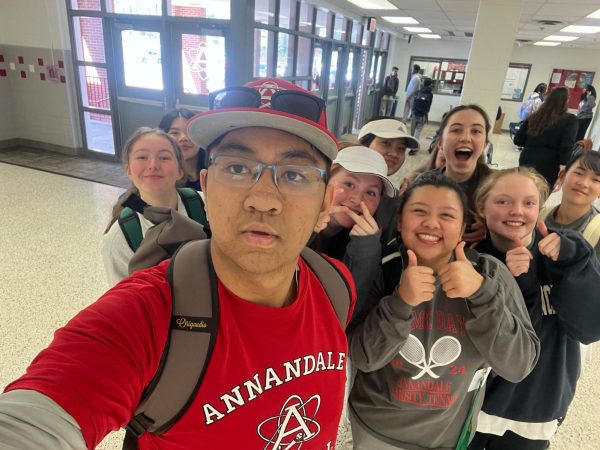 Junior John Nguyen poses for a picture with the Atoms Girls Tennis Team after providing them with a pregame motivation speech