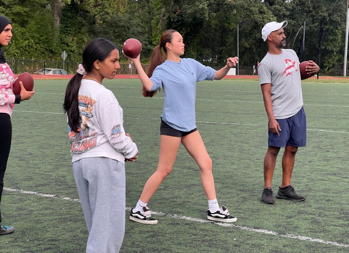 Head Coach Jewad Abdulhadi watches for the interception as freshman Sophia Do throws to her teammate at the first flag football practice on Sept. 15.