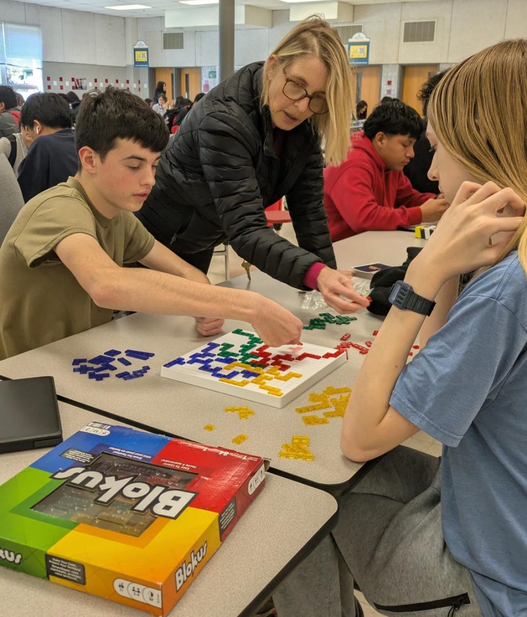 ESOL teacher Gretchen Giannelli helps juniors Charles Langille and Wyatt Allison play Blockus. Board games are always a popular pick among students.